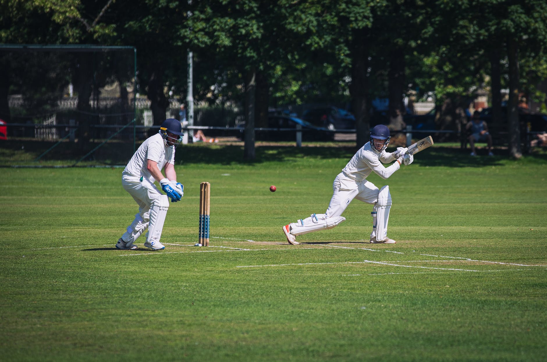 a person in white uniform playing cricket on green grass field