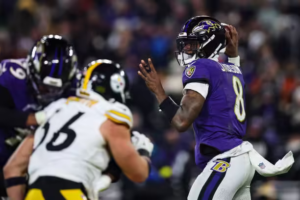 Lamar Jackson on the field behind Ravens blocker Ronnie Stanley